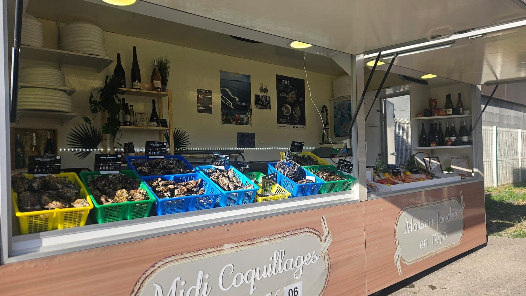 Remorque de Midi Coquillages sur le marché : paniers d'huîtres, moules et enseigne « Maison fondée en 1978 »